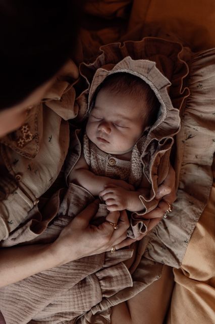 pasgeboren baby in moeders armen met prachtige ruffle badcape van biologisch katoen en mouseline